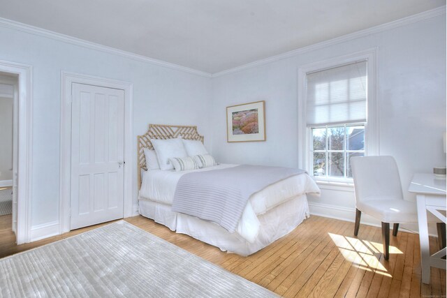 bedroom featuring ornamental molding, hardwood / wood-style flooring, and baseboards