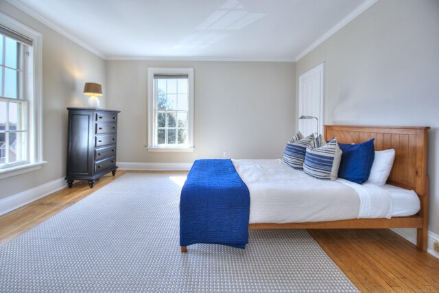 bedroom featuring baseboards, wood finished floors, and crown molding