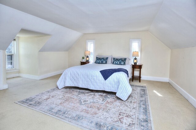 bedroom featuring lofted ceiling, multiple windows, and baseboards