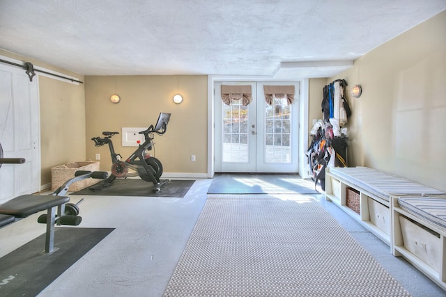 exercise area featuring a barn door, baseboards, a textured ceiling, and french doors