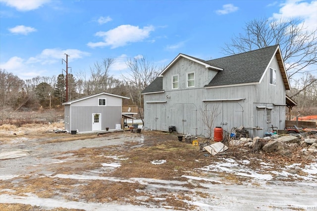 snow covered rear of property featuring an outdoor structure