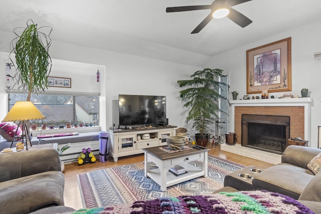 living room featuring vaulted ceiling, hardwood / wood-style floors, ceiling fan, and a fireplace