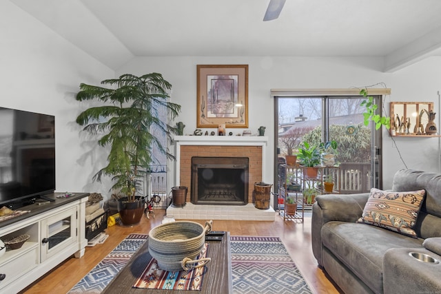 living room featuring hardwood / wood-style flooring, vaulted ceiling, ceiling fan, and a fireplace