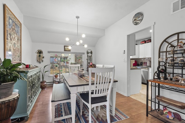 dining space with vaulted ceiling, a notable chandelier, and light hardwood / wood-style flooring