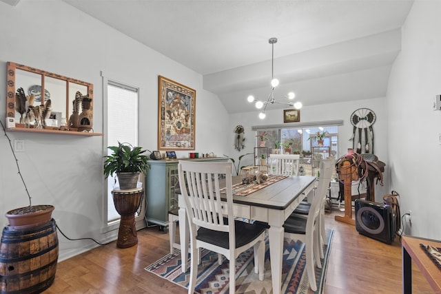 dining room featuring vaulted ceiling, hardwood / wood-style floors, and a chandelier