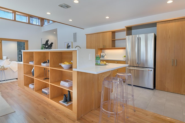 kitchen featuring stainless steel fridge, a breakfast bar area, kitchen peninsula, and light wood-type flooring