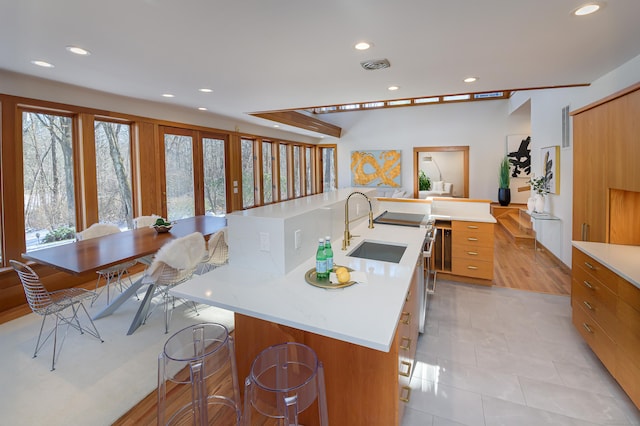 kitchen with light tile patterned flooring, sink, a center island with sink, and a kitchen bar