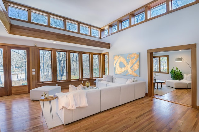 unfurnished living room featuring a high ceiling, a healthy amount of sunlight, and light wood-type flooring