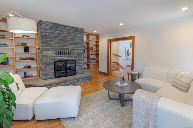 living room featuring a stone fireplace and light wood-type flooring