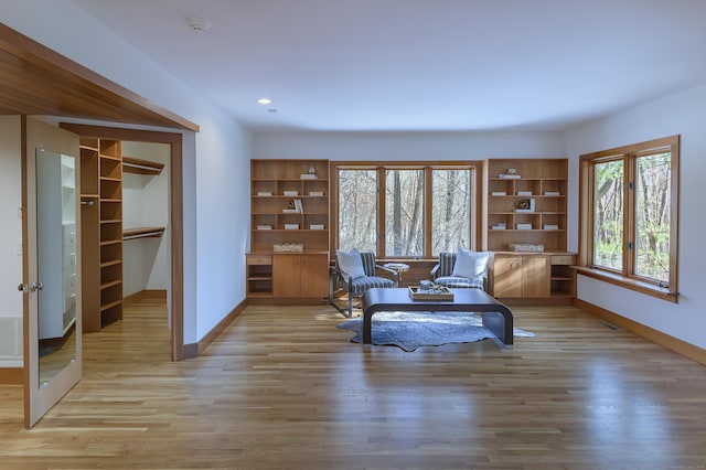 sitting room featuring light wood-type flooring and built in shelves