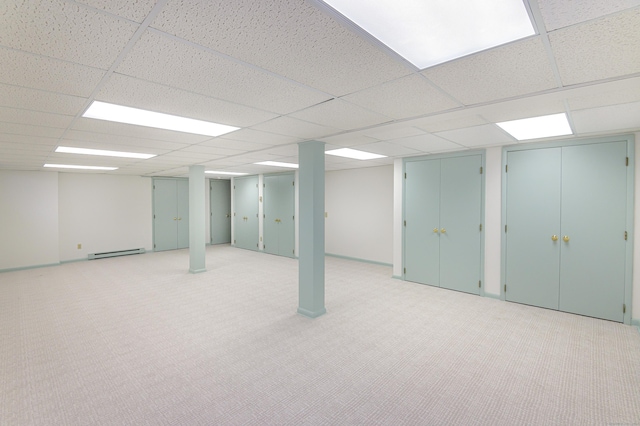 basement featuring a baseboard radiator, light colored carpet, and a paneled ceiling