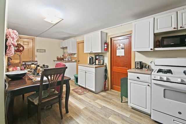 kitchen featuring white range with gas stovetop, white cabinets, and light hardwood / wood-style floors