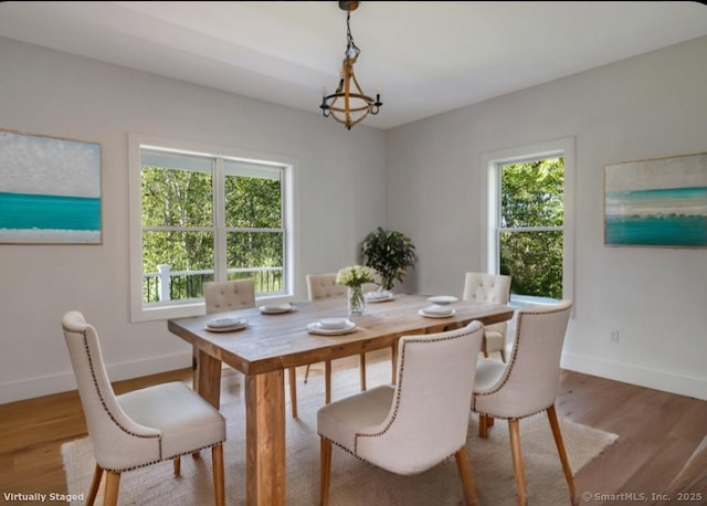 dining room with a healthy amount of sunlight, hardwood / wood-style floors, and a notable chandelier