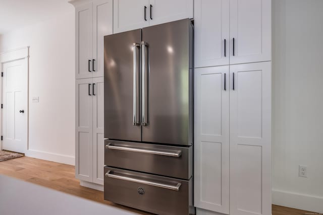 details featuring high end fridge, hardwood / wood-style floors, and white cabinets