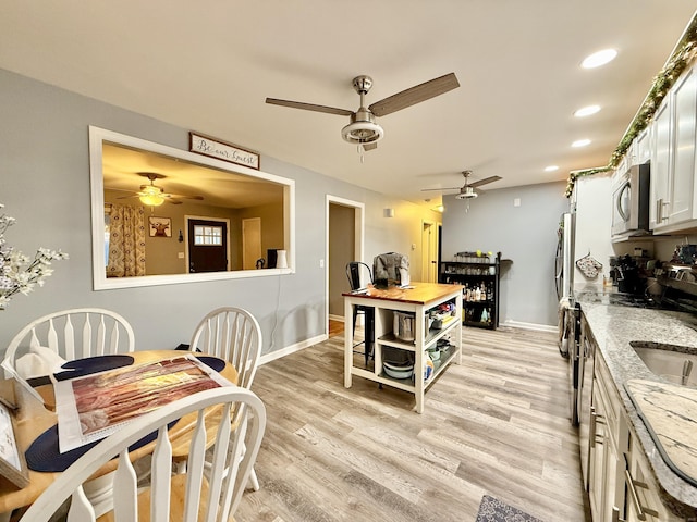 kitchen featuring white cabinetry, stainless steel appliances, light stone counters, and light hardwood / wood-style flooring