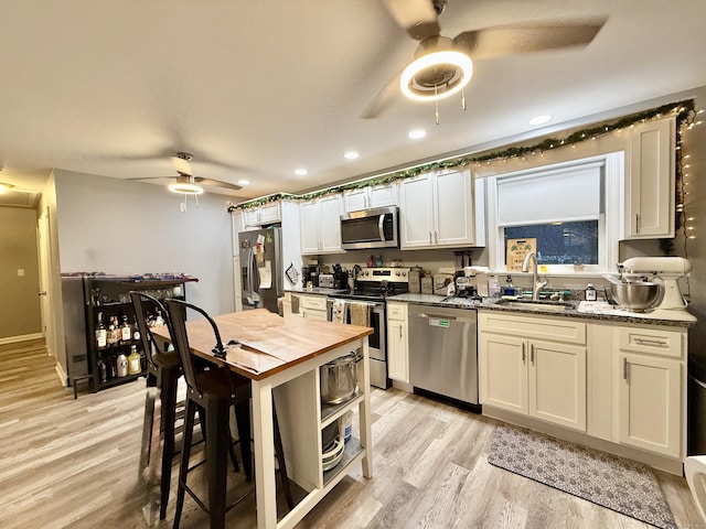 kitchen featuring white cabinetry, sink, stainless steel appliances, and dark stone counters