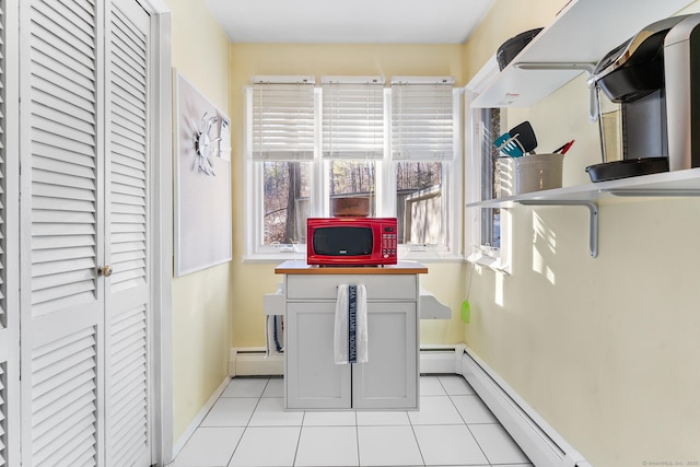 laundry area with a baseboard radiator and light tile patterned flooring