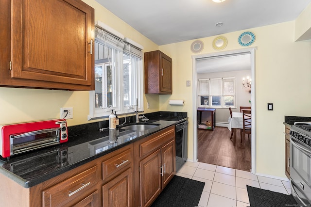 kitchen featuring light tile patterned flooring, sink, stainless steel gas stove, dark stone countertops, and dishwasher