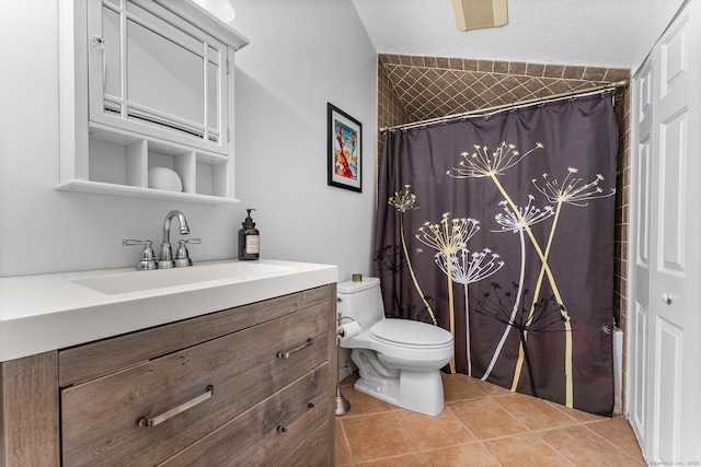 bathroom with curtained shower, vanity, toilet, tile patterned floors, and a textured ceiling