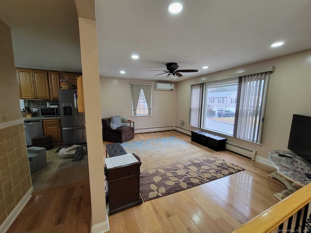 living room featuring ceiling fan, a wall mounted AC, and light wood-type flooring