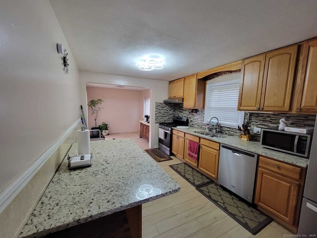 kitchen featuring appliances with stainless steel finishes, sink, backsplash, light stone counters, and a textured ceiling