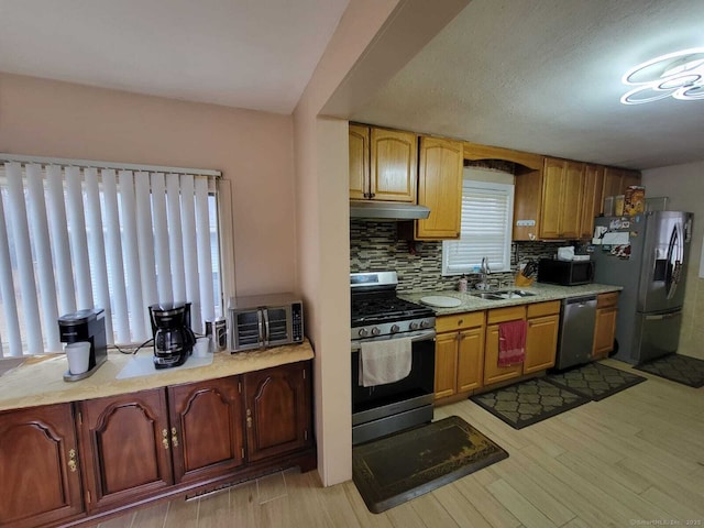 kitchen featuring tasteful backsplash, appliances with stainless steel finishes, sink, and light wood-type flooring