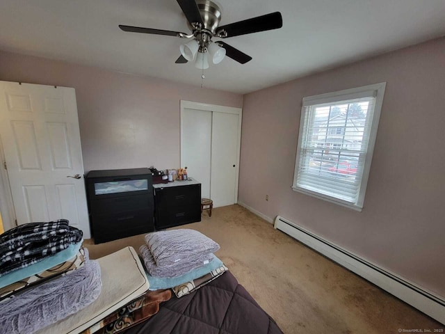 carpeted bedroom with a baseboard heating unit, a closet, and ceiling fan