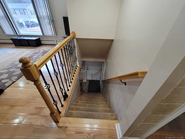 stairs featuring hardwood / wood-style floors and a baseboard heating unit