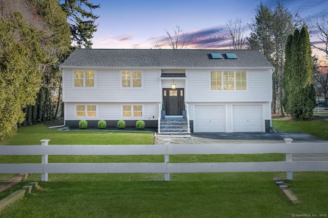 split foyer home with a garage and a lawn