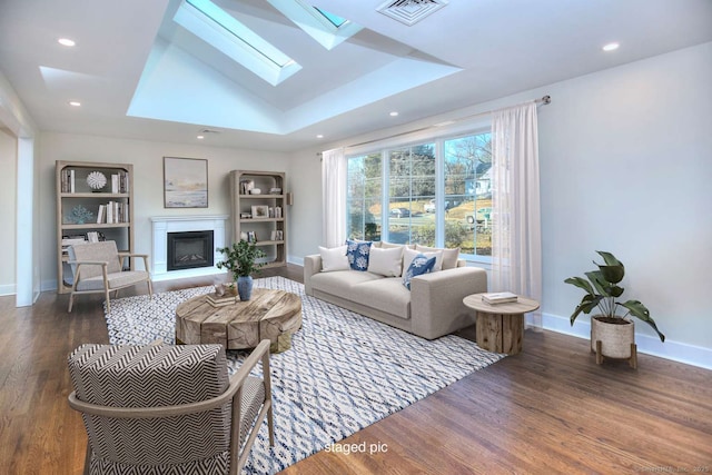 living room with dark hardwood / wood-style flooring, built in features, and lofted ceiling with skylight