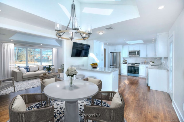 dining area featuring sink, dark wood-type flooring, a skylight, and a chandelier