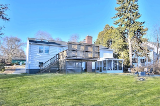 rear view of house featuring a wooden deck, a lawn, and a sunroom