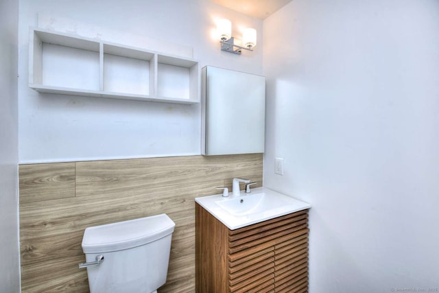 bathroom with vanity, tile walls, and toilet