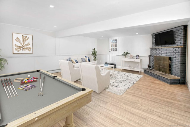 recreation room featuring pool table, a fireplace, a baseboard radiator, and light wood-type flooring