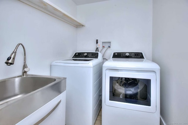 laundry room featuring sink, hardwood / wood-style flooring, and independent washer and dryer