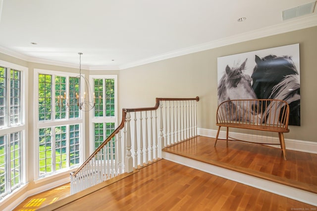 interior space featuring hardwood / wood-style flooring, crown molding, and an inviting chandelier