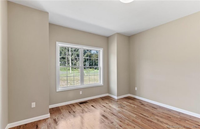 spare room featuring visible vents, baseboards, and wood finished floors