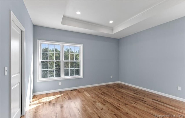 spare room featuring visible vents, baseboards, a raised ceiling, recessed lighting, and wood finished floors