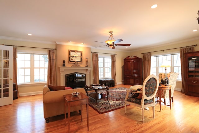 living room featuring crown molding, light hardwood / wood-style flooring, and ceiling fan