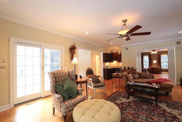 living room featuring ornamental molding, ceiling fan, and light hardwood / wood-style flooring