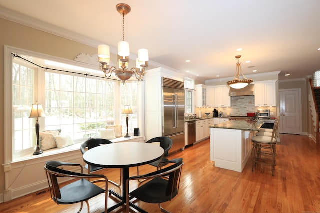 dining room featuring crown molding, sink, a notable chandelier, and light hardwood / wood-style floors