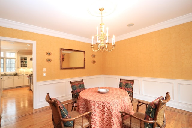 dining space featuring an inviting chandelier, crown molding, and light wood-type flooring