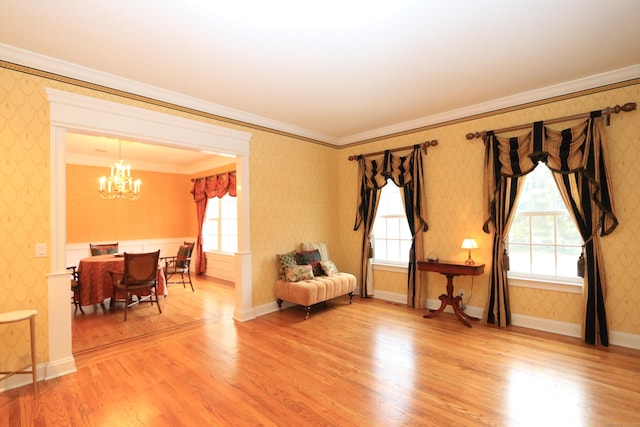 living area with an inviting chandelier, hardwood / wood-style floors, and crown molding