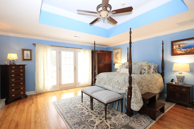 bedroom featuring light hardwood / wood-style flooring, access to outside, ornamental molding, a raised ceiling, and ceiling fan