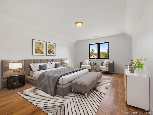 bedroom with vaulted ceiling and hardwood / wood-style floors