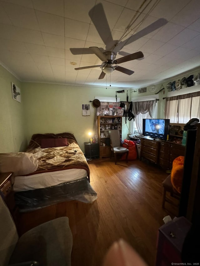 bedroom with crown molding, ceiling fan, and hardwood / wood-style floors