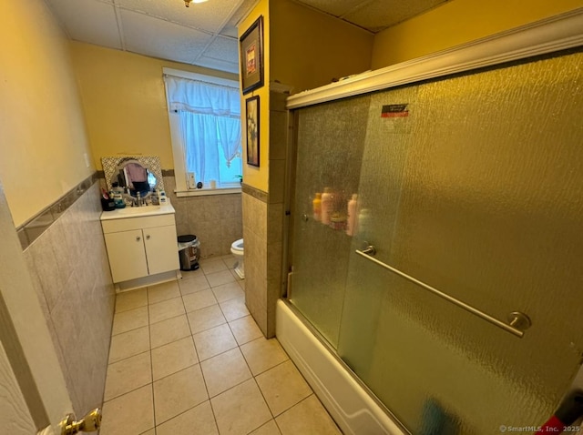 full bathroom with toilet, combined bath / shower with glass door, a paneled ceiling, vanity, and tile patterned flooring