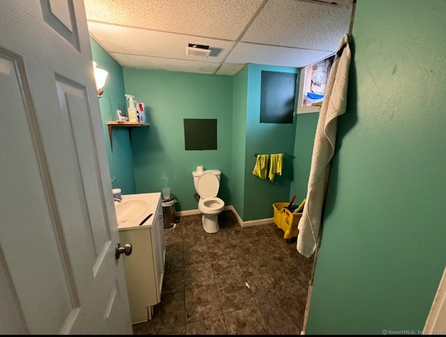 bathroom featuring vanity, toilet, and a drop ceiling