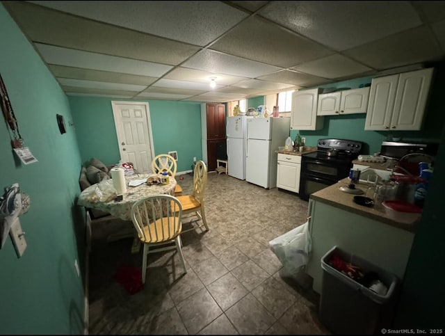 kitchen featuring a drop ceiling, white fridge, white cabinets, and range with two ovens