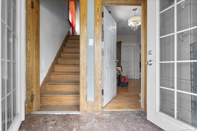 stairs featuring ornamental molding and an inviting chandelier